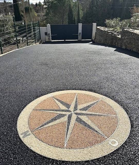 Réalisation de l'aménagement d'une cour carrossable en enrobé noir, asphalte avec une rosace personnalisé en résine drainante avec 3 coloris pour une cour sur mesure avec Daniel Moquet Aix-en-Provence 