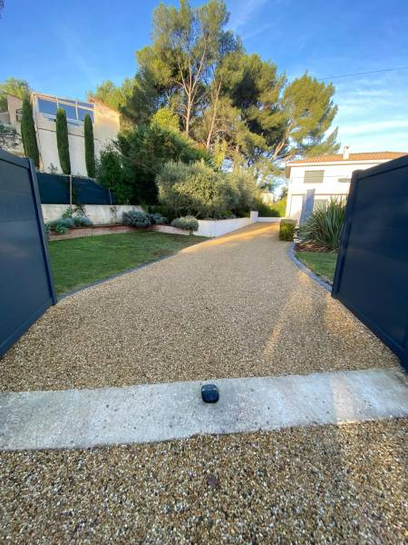 Aménagement du portail en aluminium couleur gris entracite avec cette allée d'entré carrossable en pente avec un revêtement en alvéostar gravier stabilisé avec Allées Progressives à Eguilles