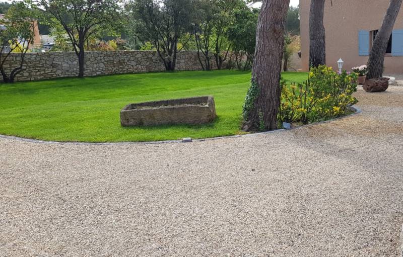 Photo d'une réalisation en gravier stabilisé gris avec contour en pavé et un aire de stationnement, parking en gravier stabilisé Alvéostar par Daniel Moquet Aix-en-Provence