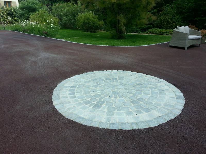 Photo de la réalisation d'un rosace en pavé LaCouture® sur une cour en enrobé rouge à chaud avec bordure en pavé par Daniel Moquet Aix-en-Provence à Venelles